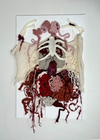 a sculpture of a skeleton covered in red yarn